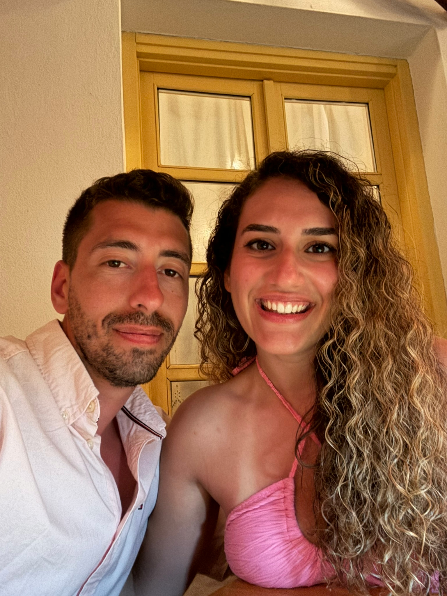 Foivos and Alexandra smiling in front of a yellow door